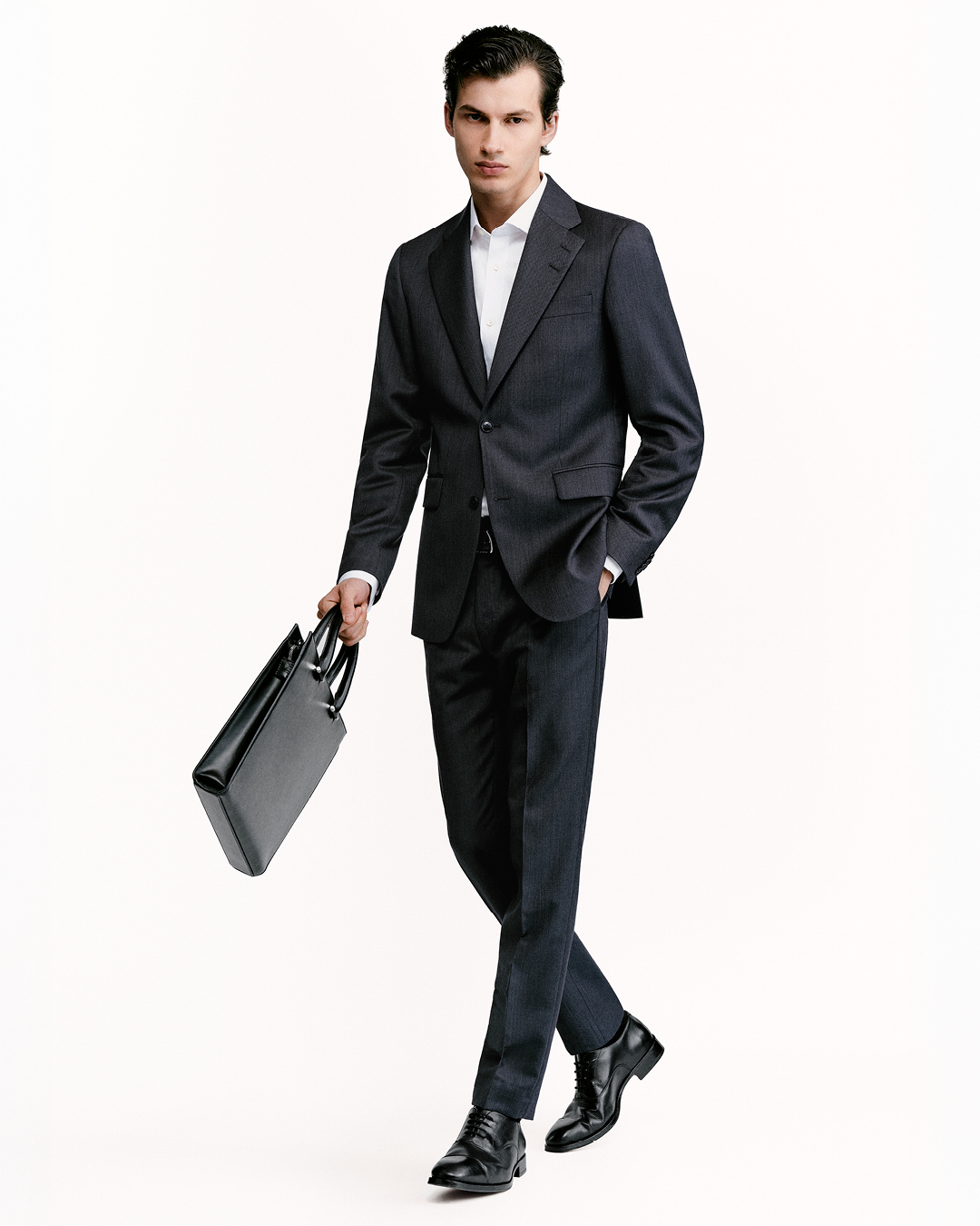 man in full black suit and computer bag